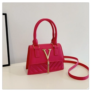Detail of magenta faux leather bag featuring a gold V-shaped logo and metallic tassel