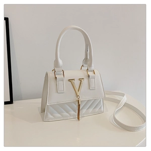 Detail of white leather handbag featuring a gold V-metal buckle with elegant chain fringe