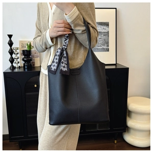 Detail of black pebbled leather tote with FASHION logo and checkered silk scarf accent