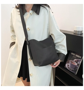 Close-up of black pebble leather bucket bag with front pocket shown on a model