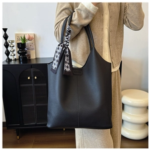 Detail of black pebbled leather tote with FASHION embossment and silk scarf handle