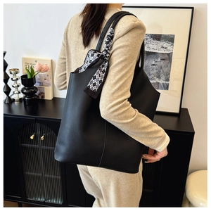 Close-up of black lychee grain leather tote bag with a chic checkered silk scarf detail