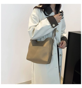 Detail of khaki leather bucket bag featuring lychee texture and adjustable shoulder strap