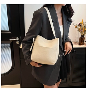Minimalist cream white pebbled leather bucket bag styled on shoulder in a home setting