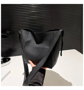 Detail of soft black litchi texture leather tote with wide shoulder strap