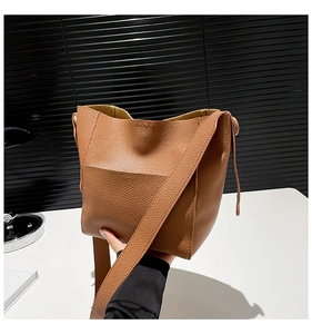 Close-up of brown lychee grain leather bucket bag with wide shoulder strap