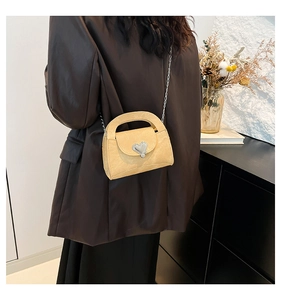 Detail of yellow crossbody bag featuring silver heart buckle and chain strap on a model