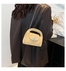 Detail of yellow crossbody bag with silver heart buckle and metal chain strap