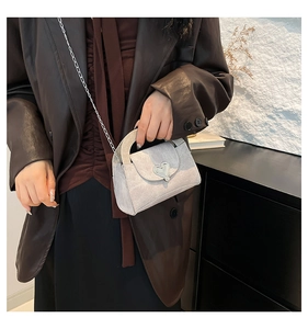 Detail of silver glitter crossbody bag featuring a metallic heart-shaped clasp and chain