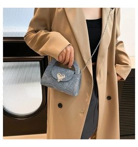 Blue denim mini handbag featuring a silver heart-shaped metal twist lock and chain strap