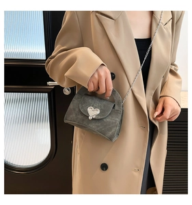 Detail of a retro chic mini crossbody bag with heart shaped silver buckle and chain