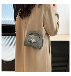 Detail of grey crossbody bag with silver heart buckle and metal chain strap