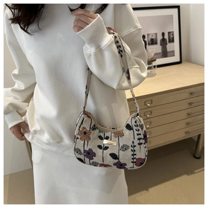 Floral jacquard crescent shoulder bag with metallic plate detail on the model