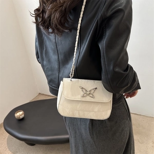 Minimalist white crossbody bag with silver butterfly buckle and chain strap on model