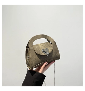 Detail of mini vintage denim crossbody bag featuring a silver heart metal buckle and chain
