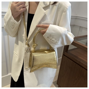 Close-up of golden embossed crocodile leather bag with iconic hourglass curved base
