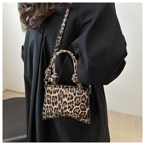 Détail du sac à main léopard avec poignée nouée et finitions dorées porté par un mannequin