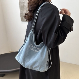 Blue denim tote bag with Less Monday More Sunday embroidery worn by a model