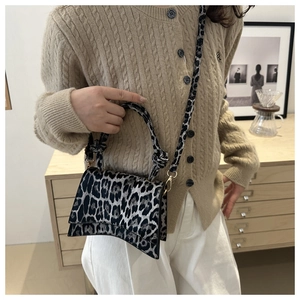 Détail du sac à main léopard avec base incurvée et bandoulière sur un mannequin