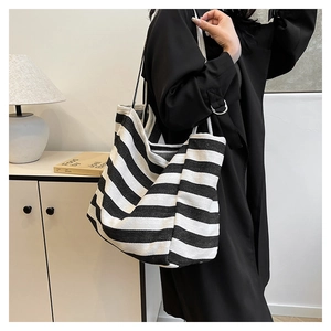 Close-up of a striped canvas tote bag with black straps in a minimalist home setting