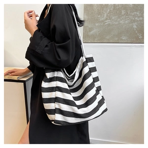 Close-up of wide canvas strap and large striped tote bag on model for casual wear