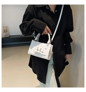 Detail of white square bag featuring heart cutout and faux leather bow decoration