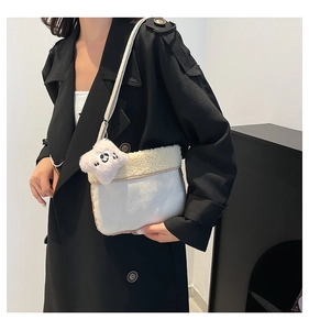 Gros plan sur un sac bandoulière en peluche blanche avec détails polaires et pendentif