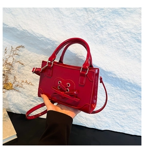 Detail view of red patent leather crossbody bag with heart quilting and bow detail
