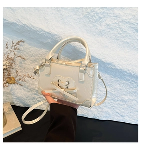 Detail of white handheld crossbody bag with heart cut-out and sweet bow decoration