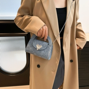 Light blue denim handbag with silver heart buckle and chain strap shown with a trench coat