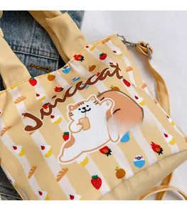 Close-up of yellow canvas bucket bag with cute cat, strawberry, and bread graphics