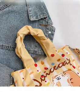 Detail of a yellow striped canvas bucket bag with cute cartoon prints and twisted handles