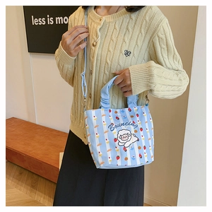 Lifestyle view of light blue striped bucket bag with sheep print and adjustable strap