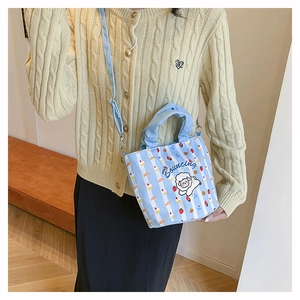 Detail of light blue striped bucket bag with cute sheep pattern and strawberry design