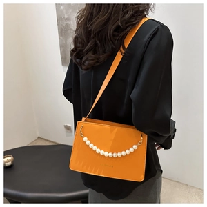 Detail of trendy orange square shoulder bag with stylish pearl chain and fashion text