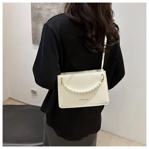 Close-up of a white glossy crossbody bag with pearl chain detail and FASHION lettering