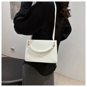 Close-up of off-white faux leather crossbody bag with pearl chain and fashion text
