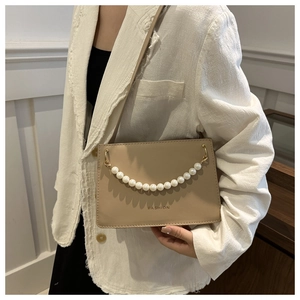 Detail showing the beige leather shoulder bag with FASHION text and elegant pearl chain