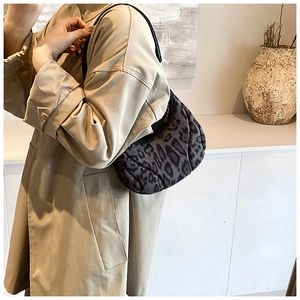 Détail du sac léopard matelassé porté avec un trench beige dans un décor minimaliste
