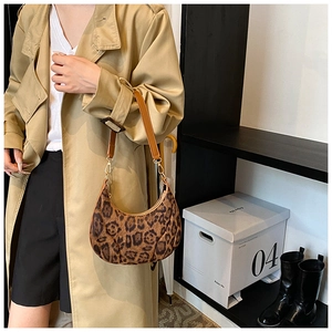 Détail du sac hobo en forme de croissant à motif léopard porté avec une bandoulière brune