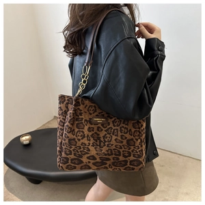 Detail of leopard print tote bag with brown leather brand tag and metal chain strap