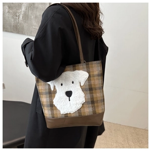 Detail of checkered tote bag featuring a cute dog patch worn by a model in black coat