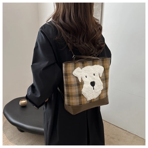 Rear view of a model wearing a brown plaid backpack with a cute schnauzer embroidery patch