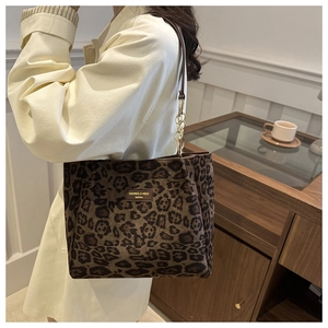Detail of leopard print tote bag featuring leather straps and gold chain link accents