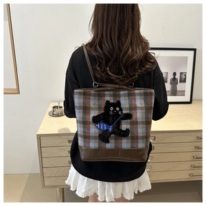 Detail of plaid tote bag featuring cartoon cat embroidery and brown leather straps