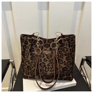 Detail of leopard print tote bag with brown leather handle and gold chain on chair