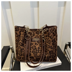 Detail of leopard print tote bag with brown leather handles and decorative gold chain strap