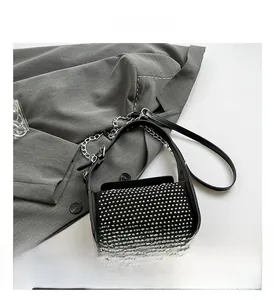 Detailed view of black rivet shoulder bag with silver chain strap and suede flap