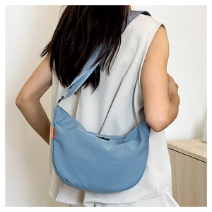 Detail showing high-quality nylon fabric texture and orange tag on the blue dumpling bag