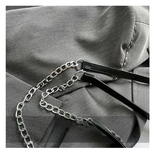 Detail of silver metal chain strap and black leather stitching on a trendy crossbody bag